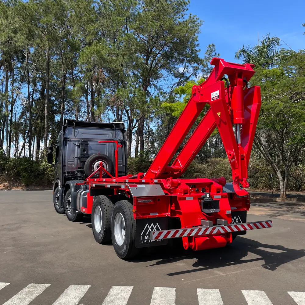 Caminhão com equipamento Roll-On/Roll-Off IMAVI vermelho, com o braço do gancho levantado